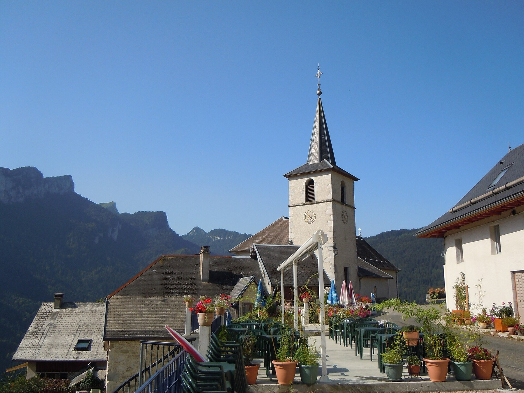 Le clocher de Corbel et la terrasse fleurie face aux falaises